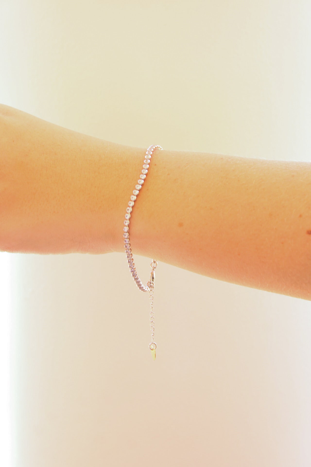 Braha Stevie Tennis Bracelet featuring sparkling stones and delicate chain, displayed on a neutral background.