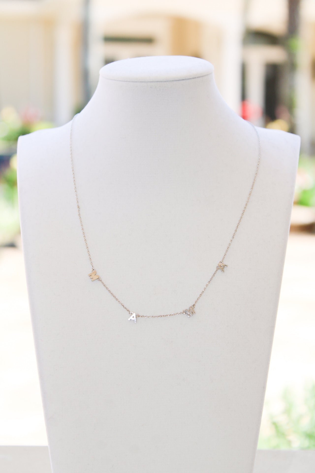 Gold "MAMA" necklace jewelry by Golden Stella featuring a delicate pendant on a fine chain.