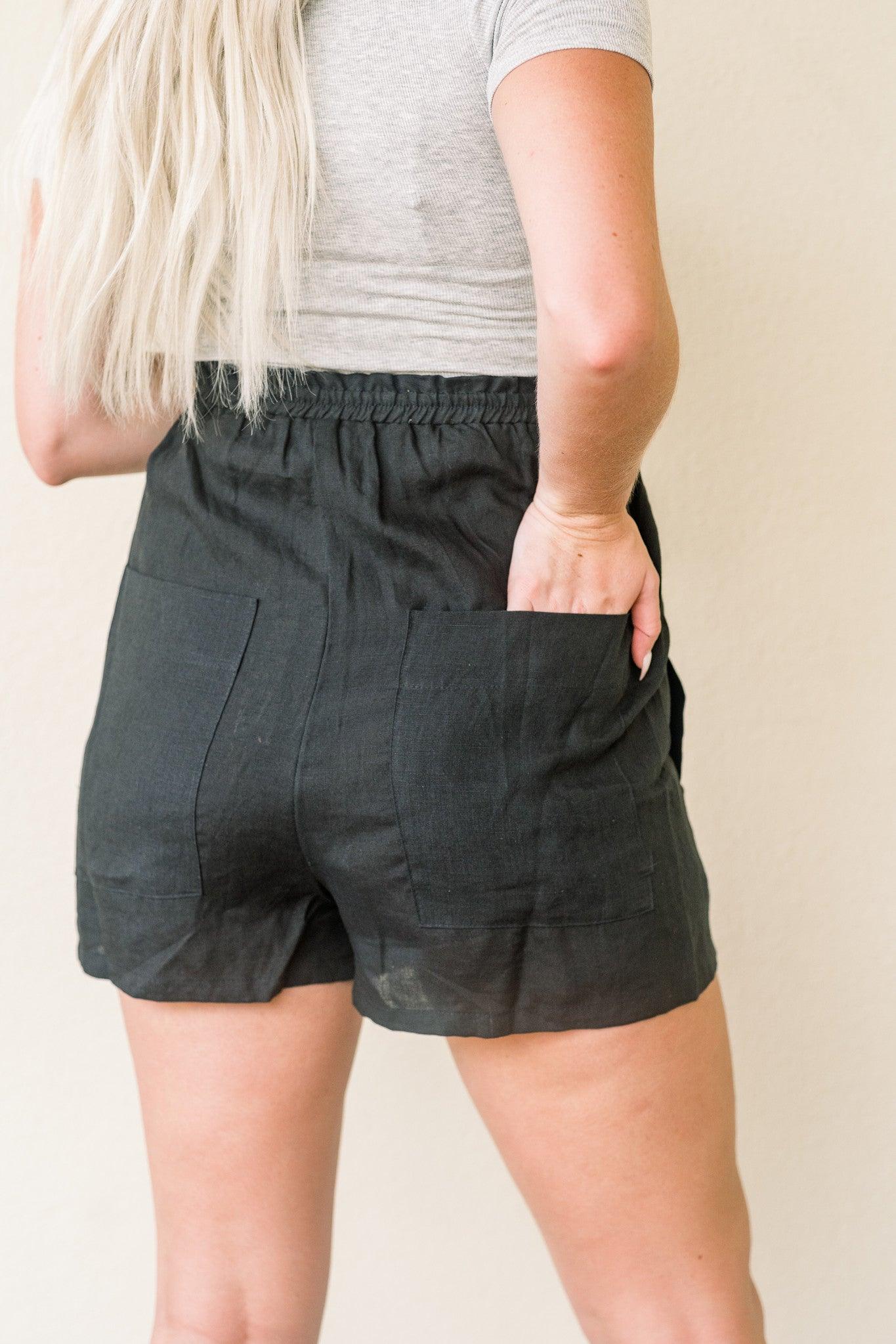 Black super high-waisted Barbie shorts by Olivaceous LA with a fitted style, shown hanging on a white background.