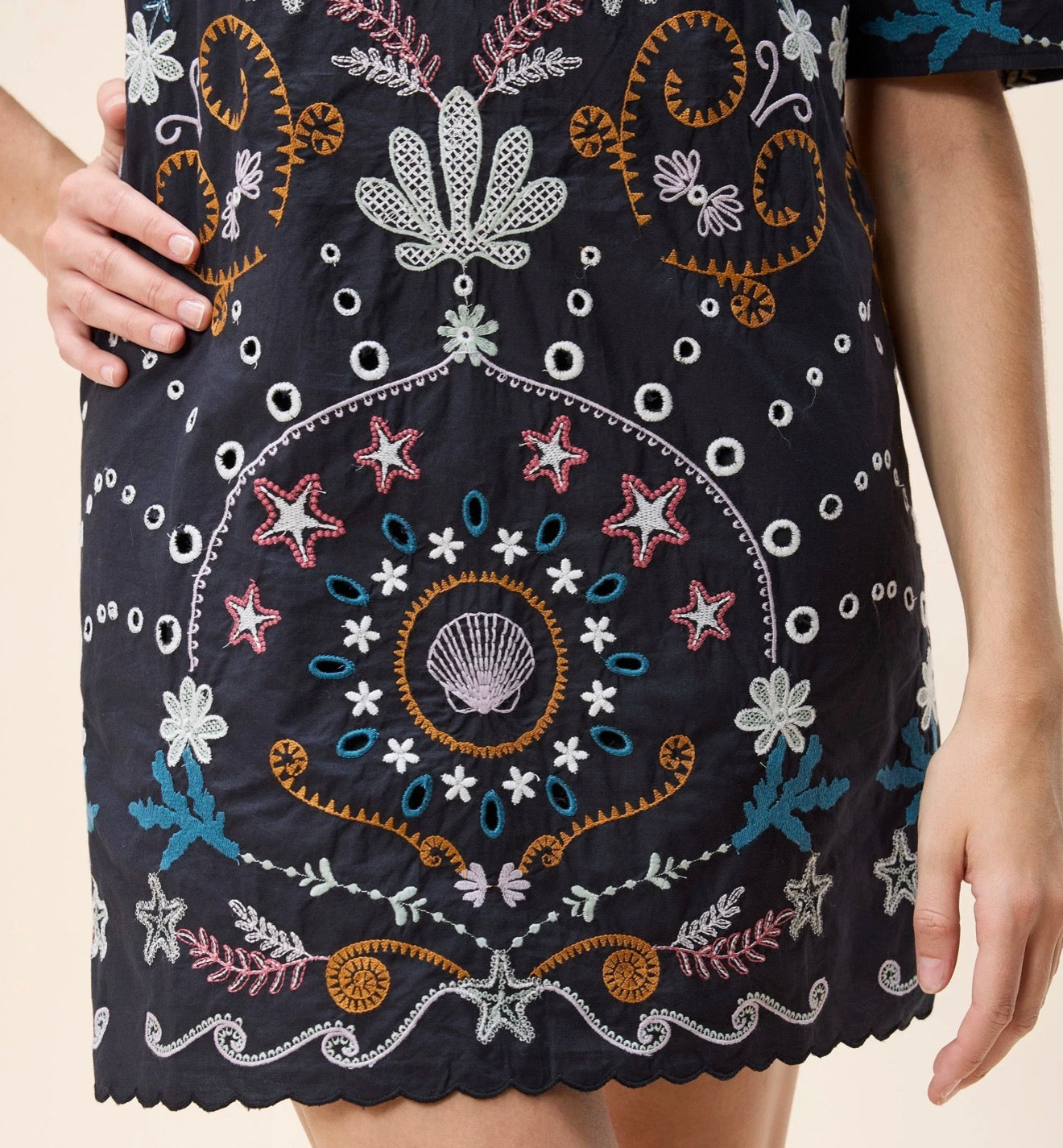 Black Mische mini dress by CLEOBELLA displayed on a hanger with a close-up view of the fabric and design details.